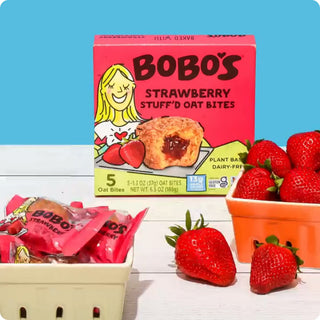 Bobo's Strawberry Stuff'd Oat Bites packaging displayed next to baskets of strawberries on a blue background